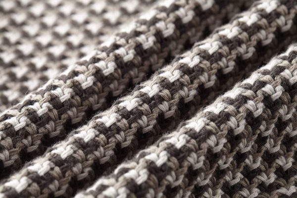 The jacket is brown and beige with a houndstooth-like pattern across the main body, and has solid, dark brown sleeves with a different knit texture