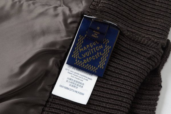 The jacket is brown and beige with a houndstooth-like pattern across the main body, and has solid, dark brown sleeves with a different knit texture