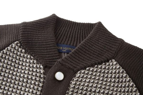 The jacket is brown and beige with a houndstooth-like pattern across the main body, and has solid, dark brown sleeves with a different knit texture