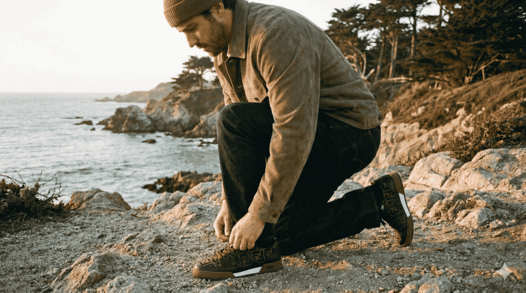 A man lacing up his FF FENDI sneakers