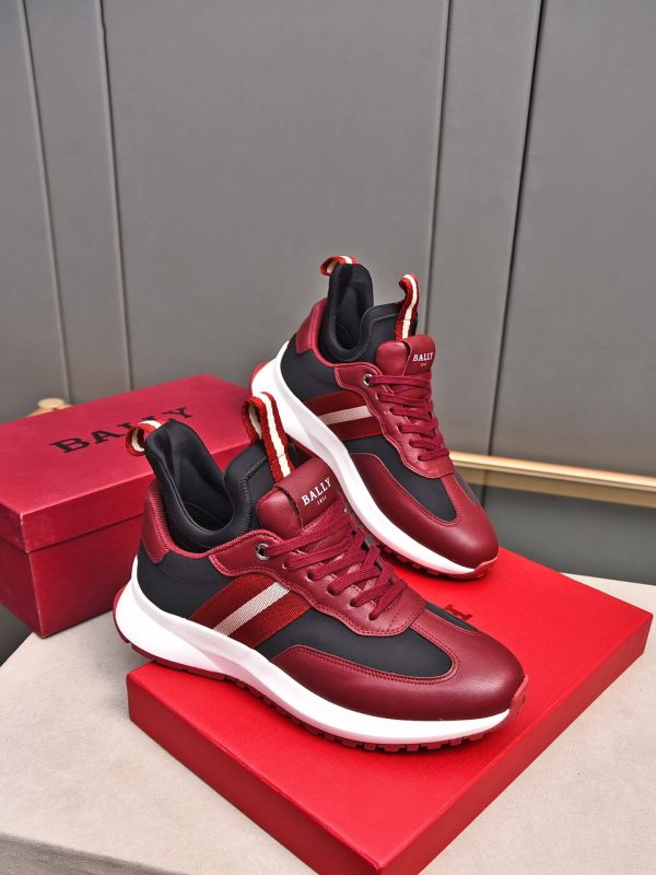 A pair of Bally Mixed-Material Runner Sneakers in burgundy and black resting on top of a red Bally shoebox.