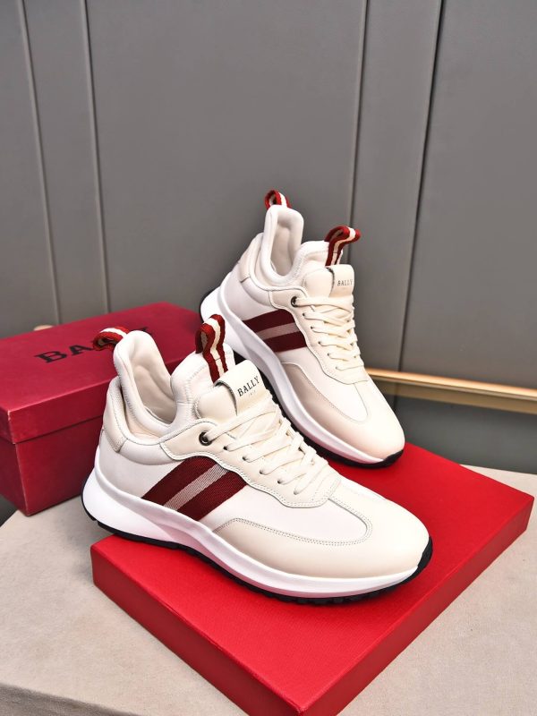 A pair of Bally Striped Leather Runner Sneakers in white and cream featuring burgundy side stripes and woven pull tabs, resting atop a red branded Bally shoebox.