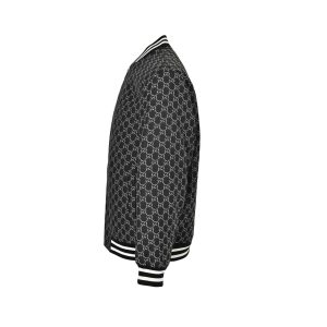 Side profile view of the black and white Gucci GG Monogram bomber jacket displaying the all-over pattern and striped ribbed cuffs.